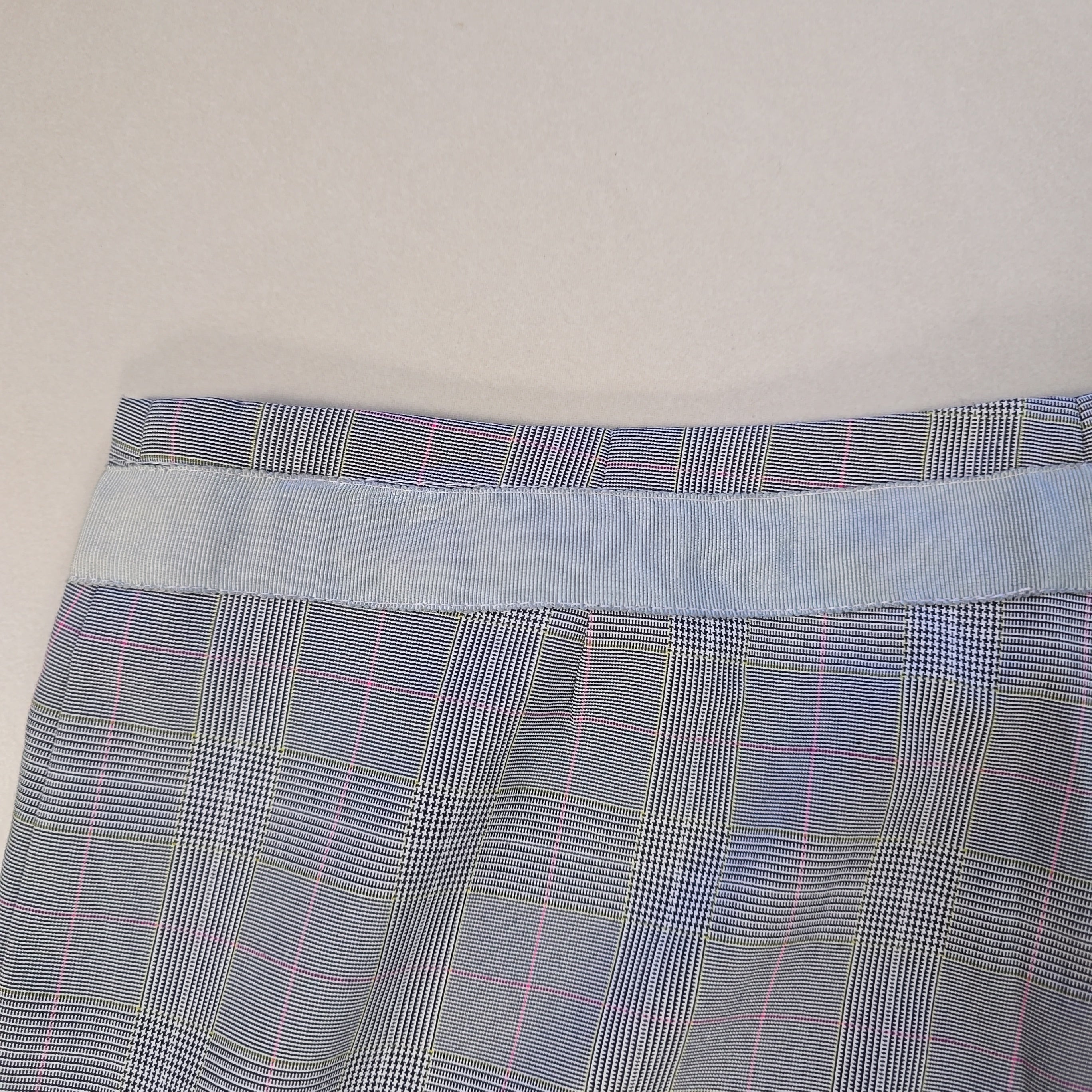 Close-up of plaid fabric with a visible seam on a light gray background