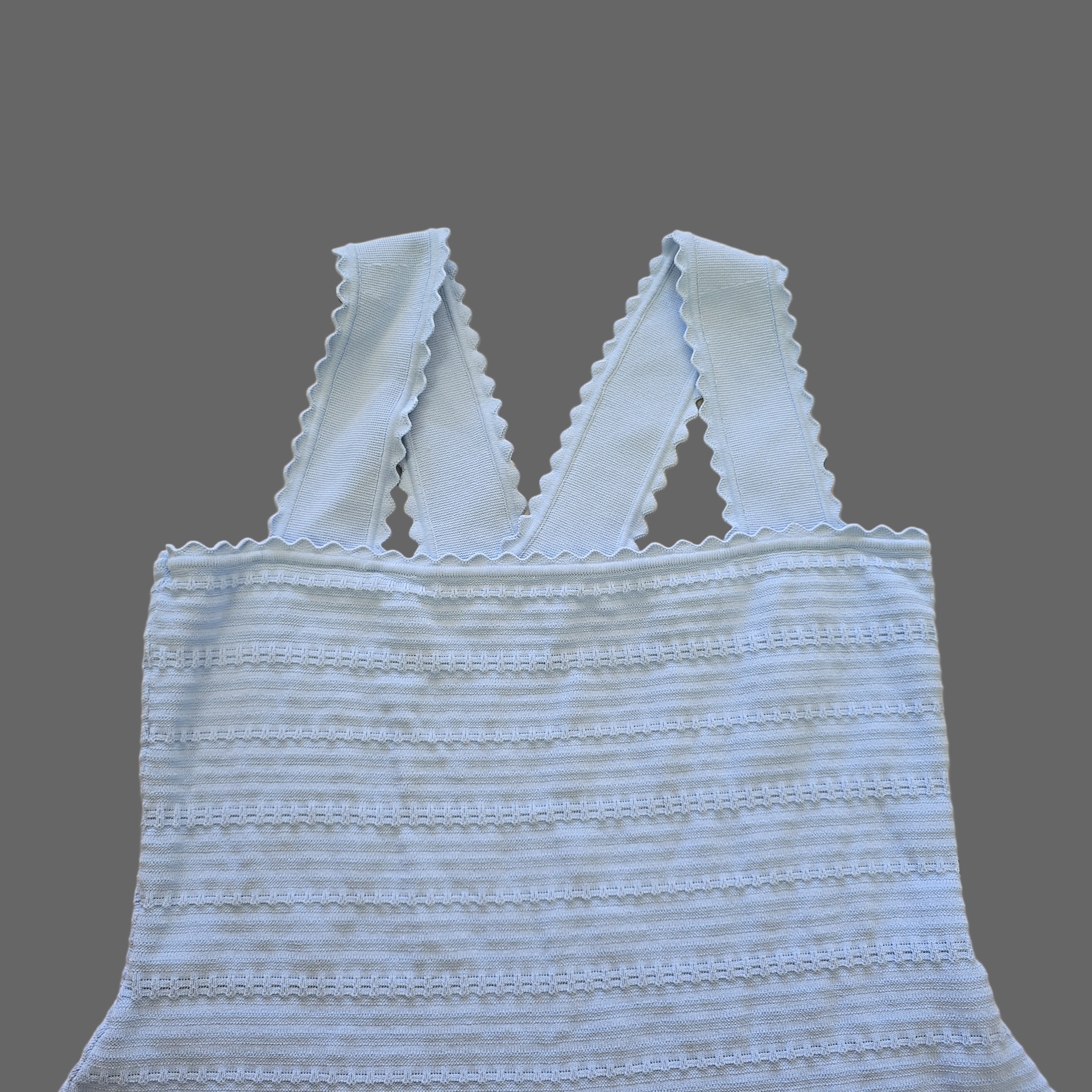 Light blue textured top with thin straps on a beige tiled floor