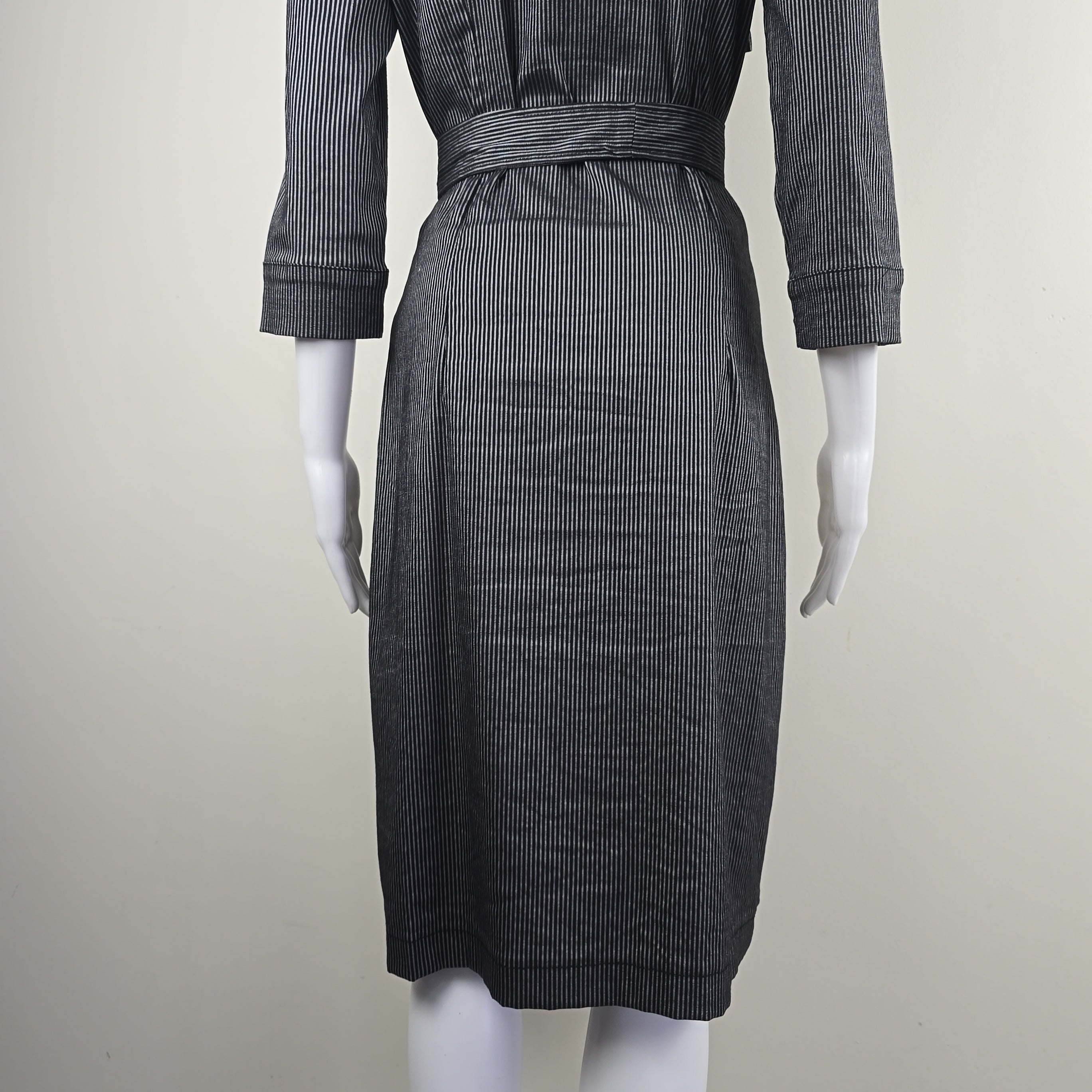 Mannequin wearing a black and gray striped dress on a plain background