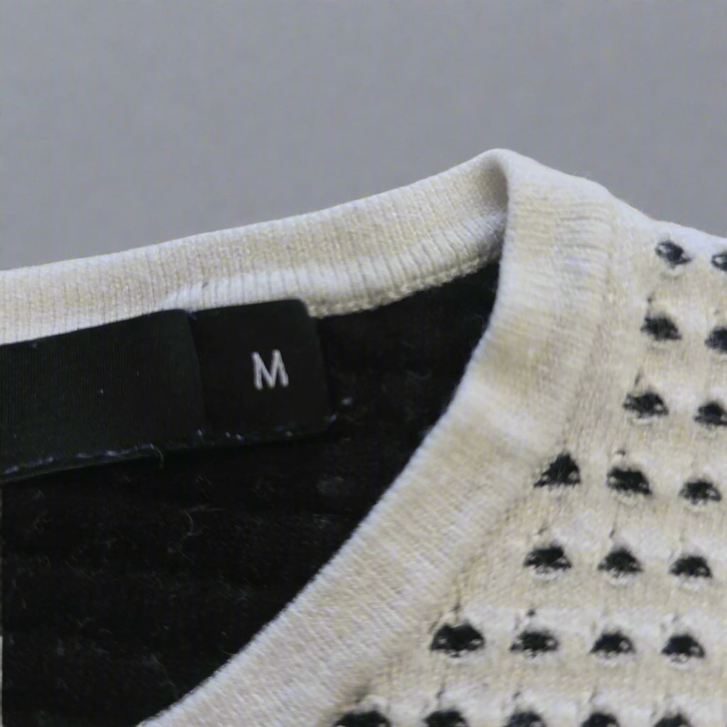 Close-up of a sweater with a brand tag on a beige background