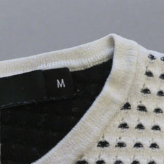 Close-up of a sweater with a brand tag on a beige background