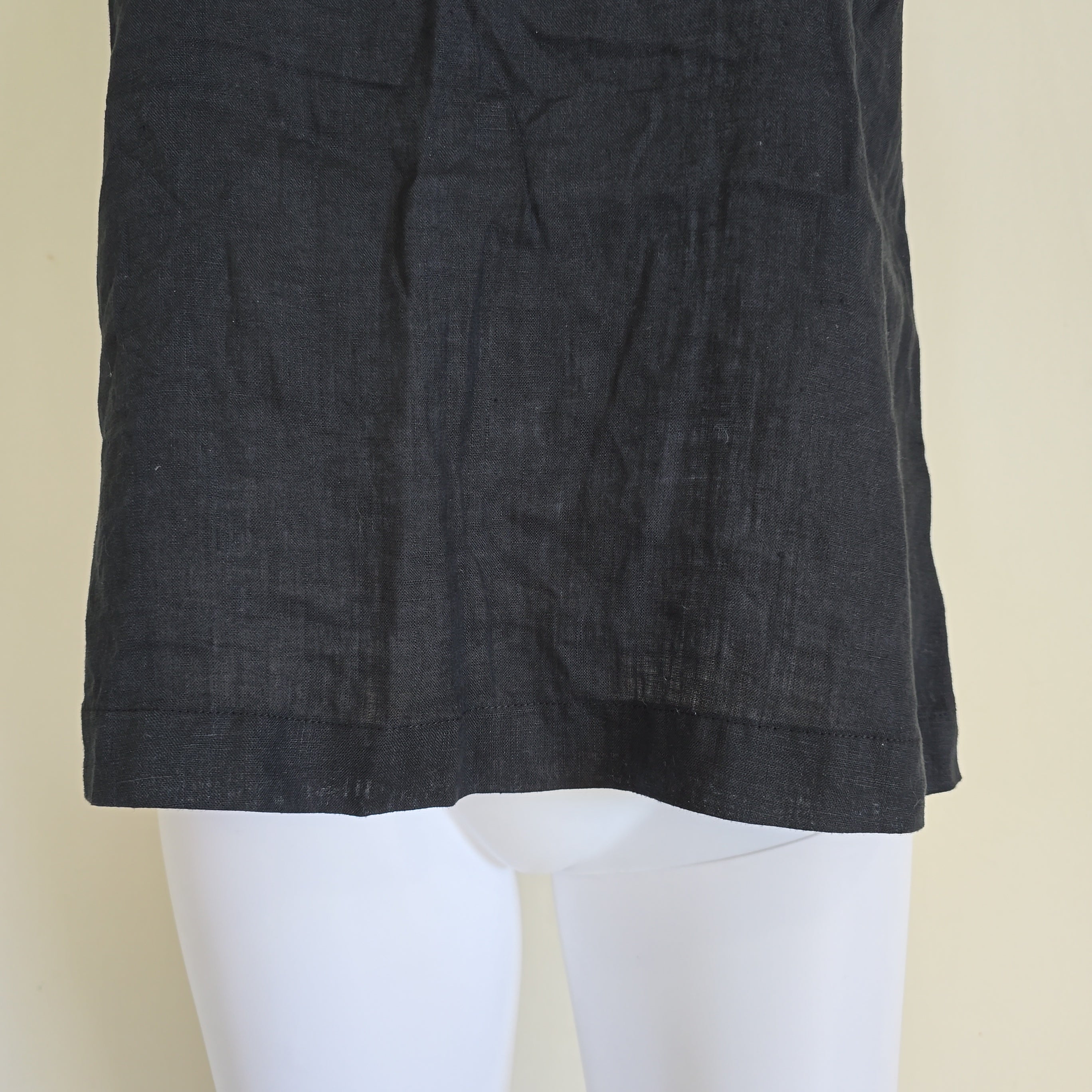 Black fabric draped over a white mannequin on a beige background