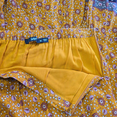 Mustard yellow fabric with floral pattern and a visible tag.