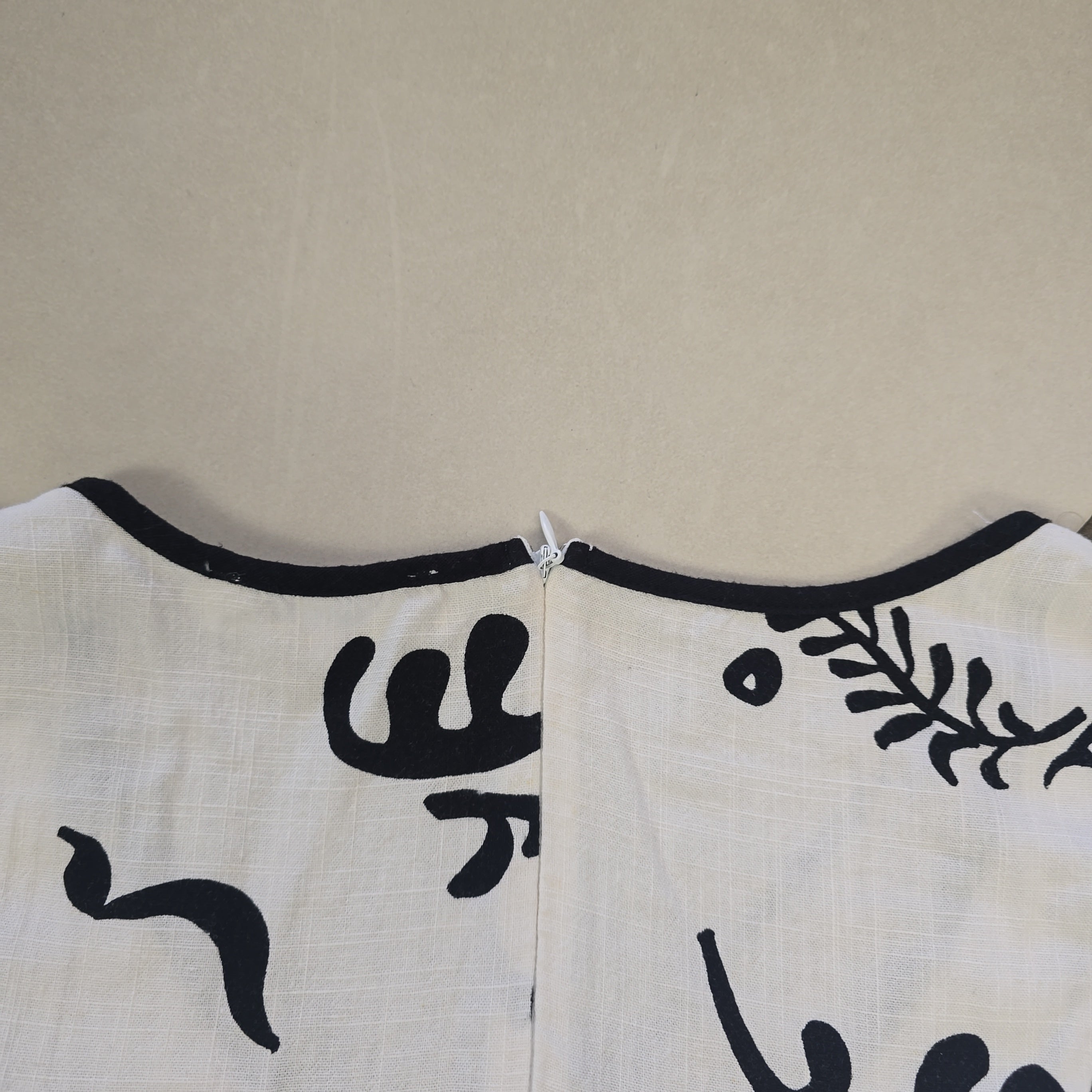 White apron with black floral patterns on a beige background