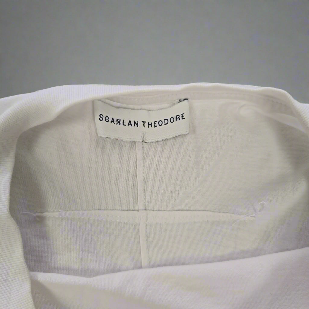 Close-up of a white garment with a visible brand label on a neutral background