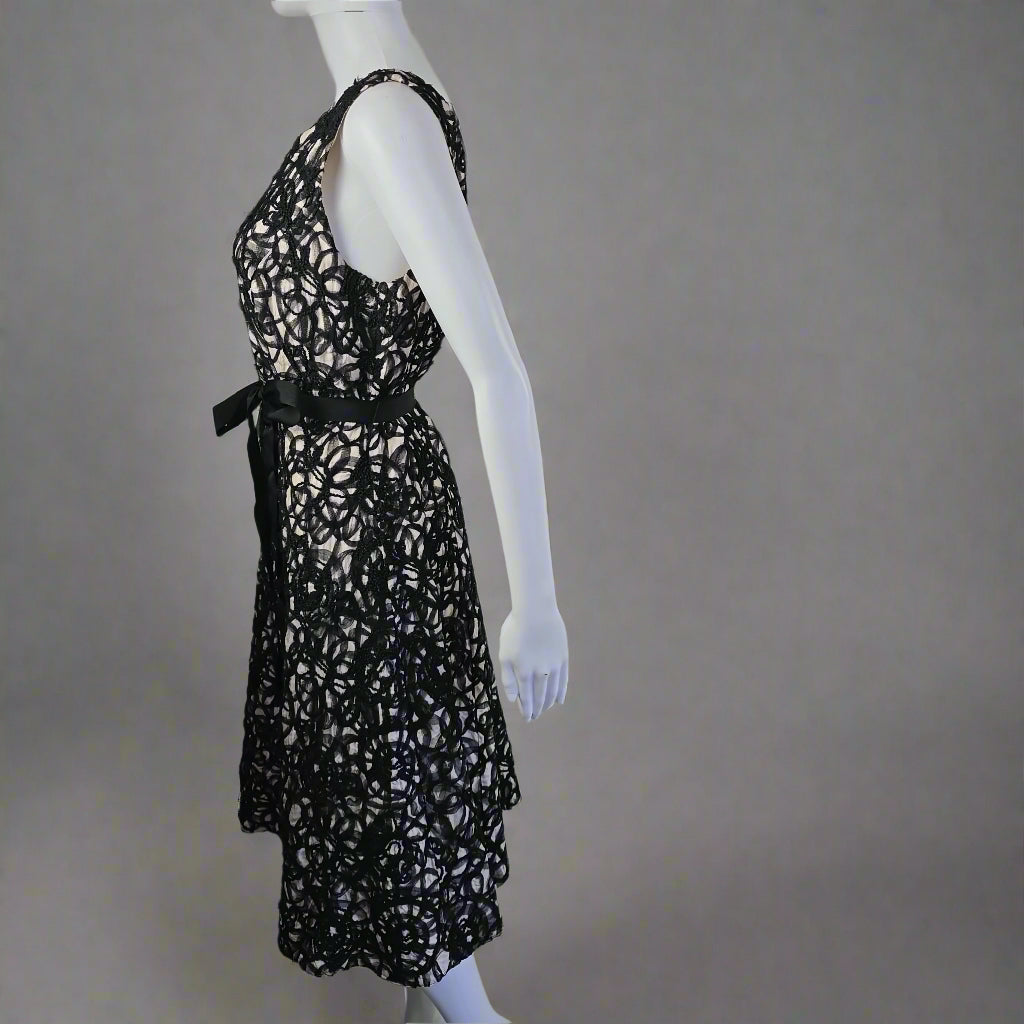 Black lace dress on a mannequin against a white wall