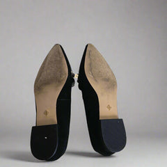 Black pointed-toe shoes on a tiled floor