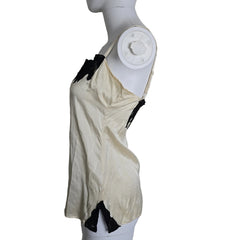 Mannequin wearing a white top with black lace details on a plain background