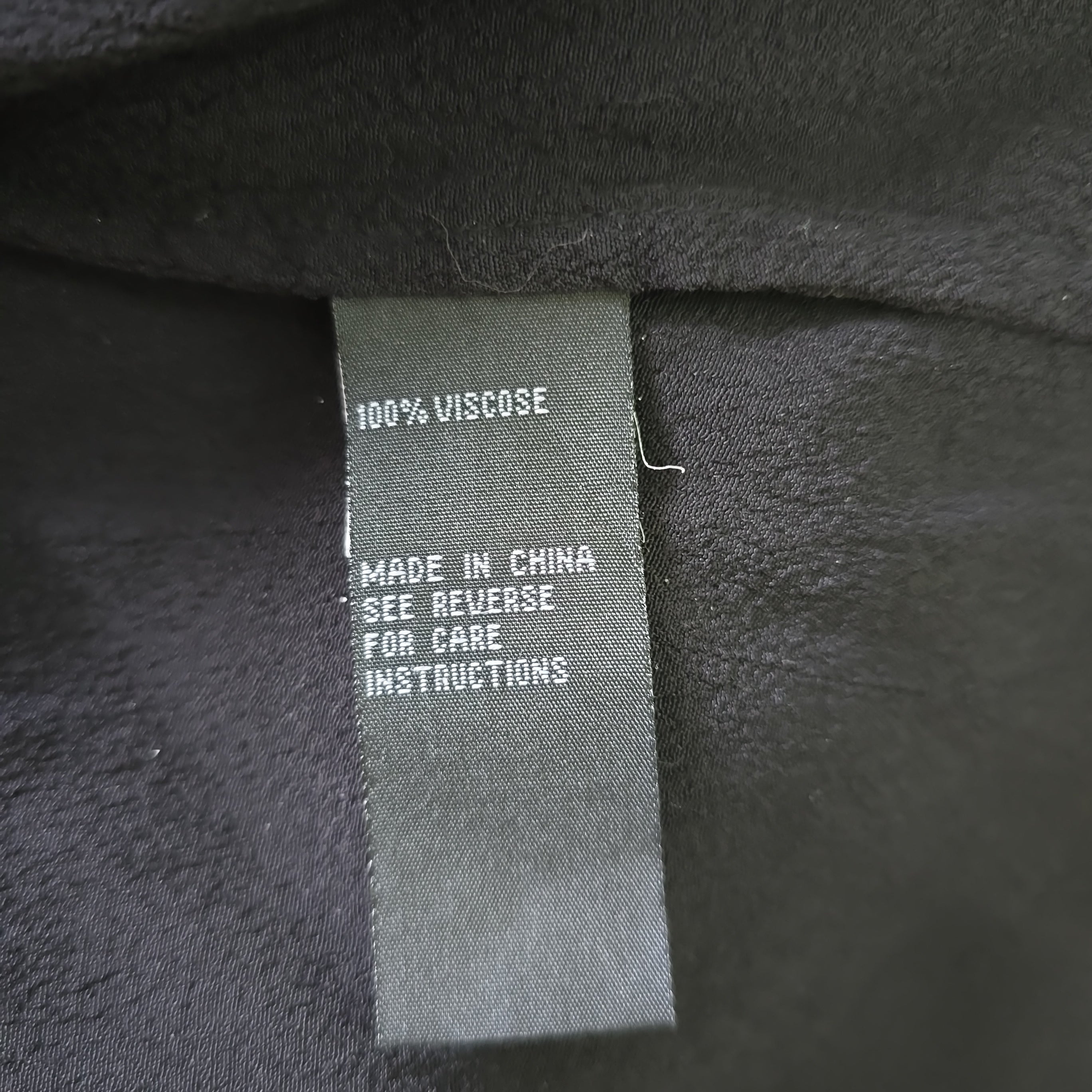 Fabric tag on black fabric with text about material and care instructions.