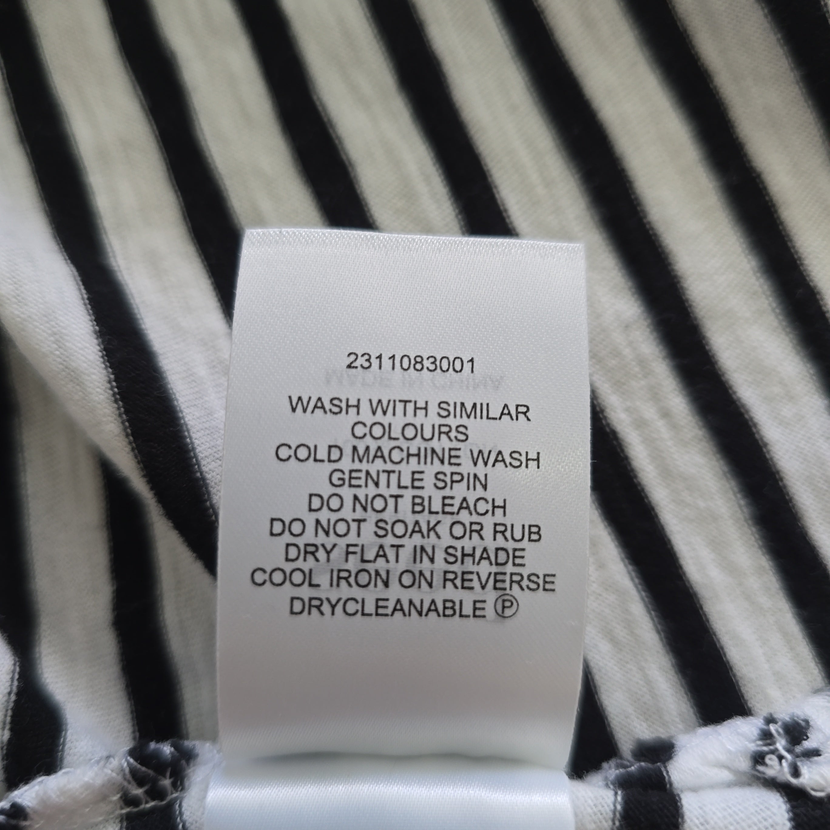 Clothing label on a black and white striped fabric background