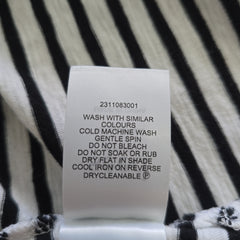 Clothing label on a black and white striped fabric background