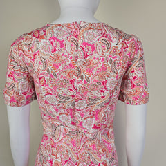 Pink paisley patterned fabric on a mannequin against a plain background