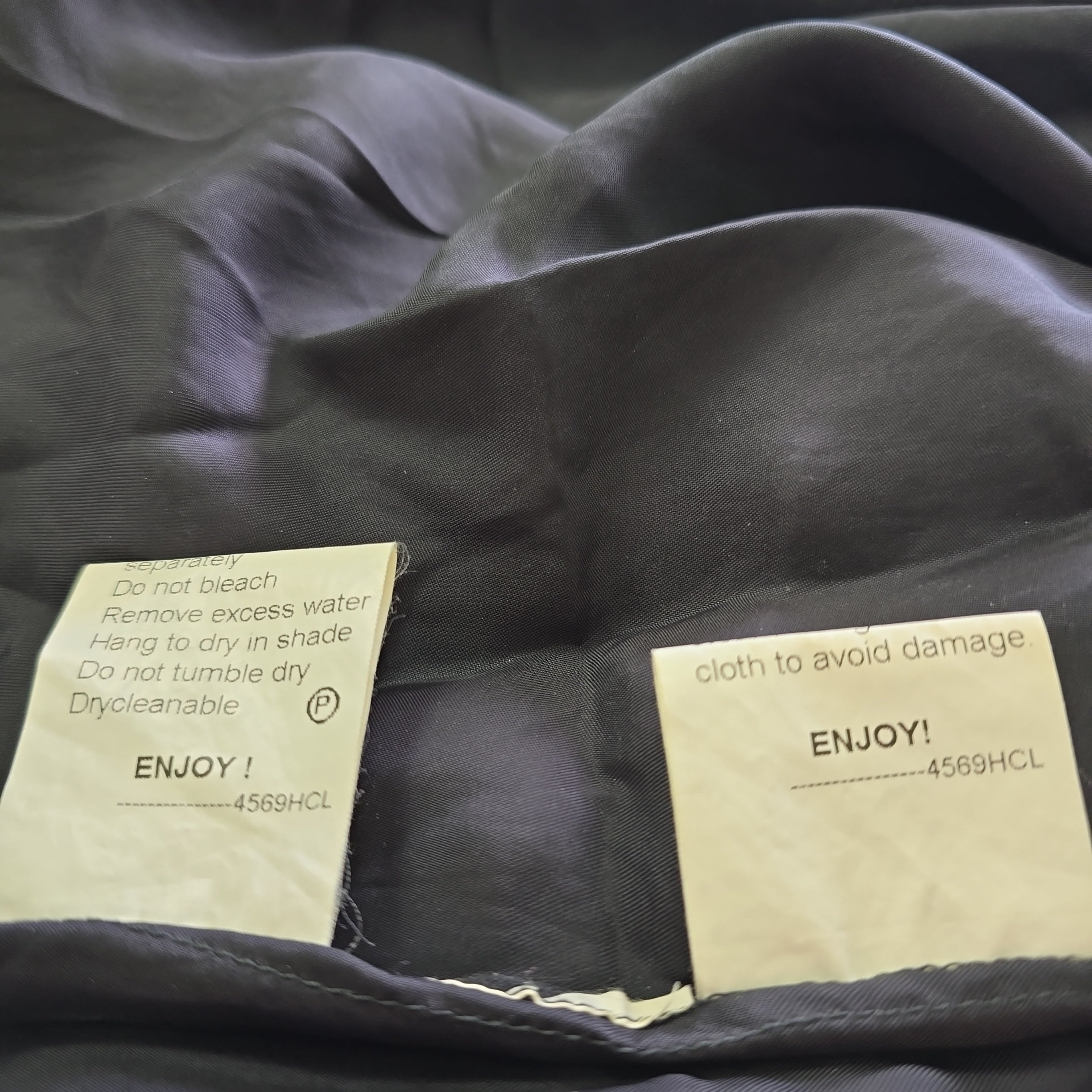 Close-up of dark fabric with 'ENJOY!' labels on a textured background