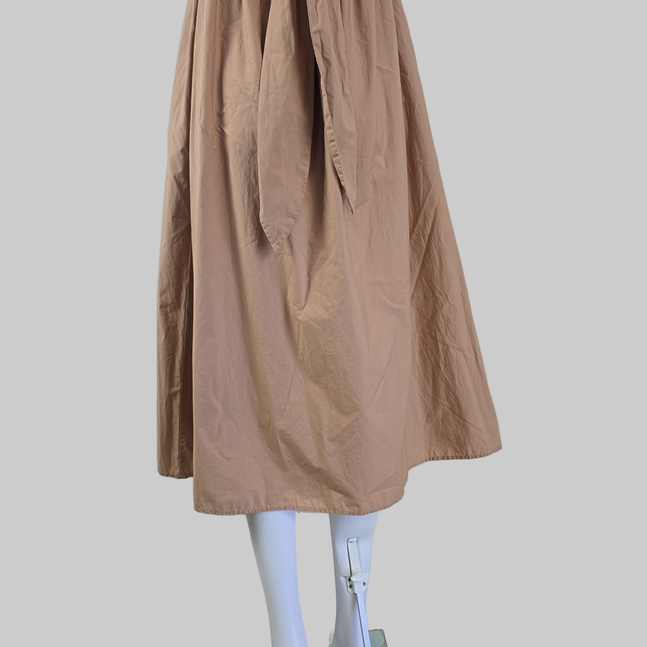 Brown dress against a white wall