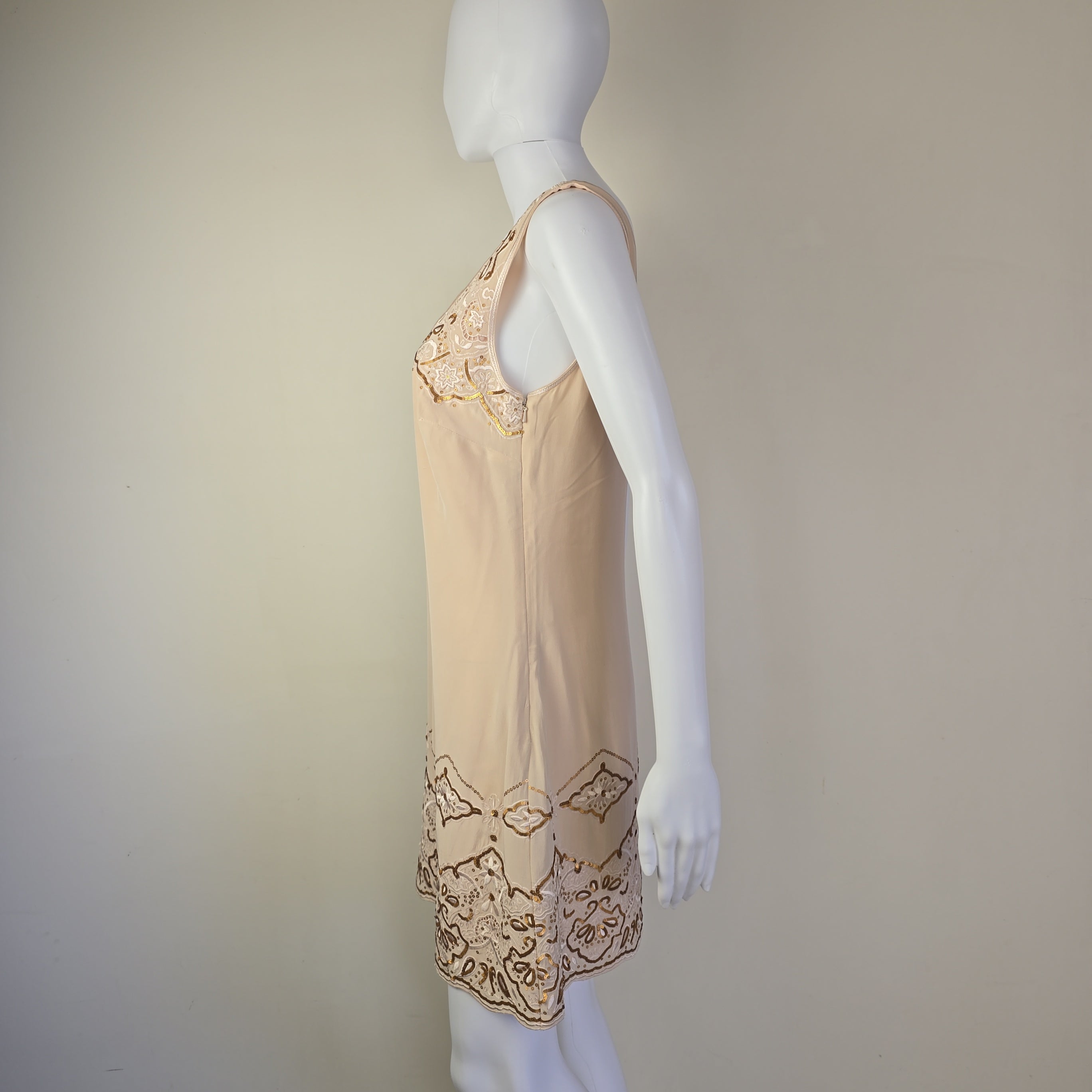 Mannequin wearing a beige dress with lace details on a plain background