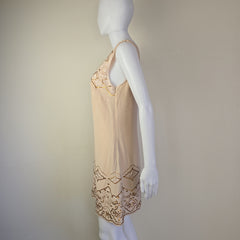 Mannequin wearing a beige dress with lace details on a plain background