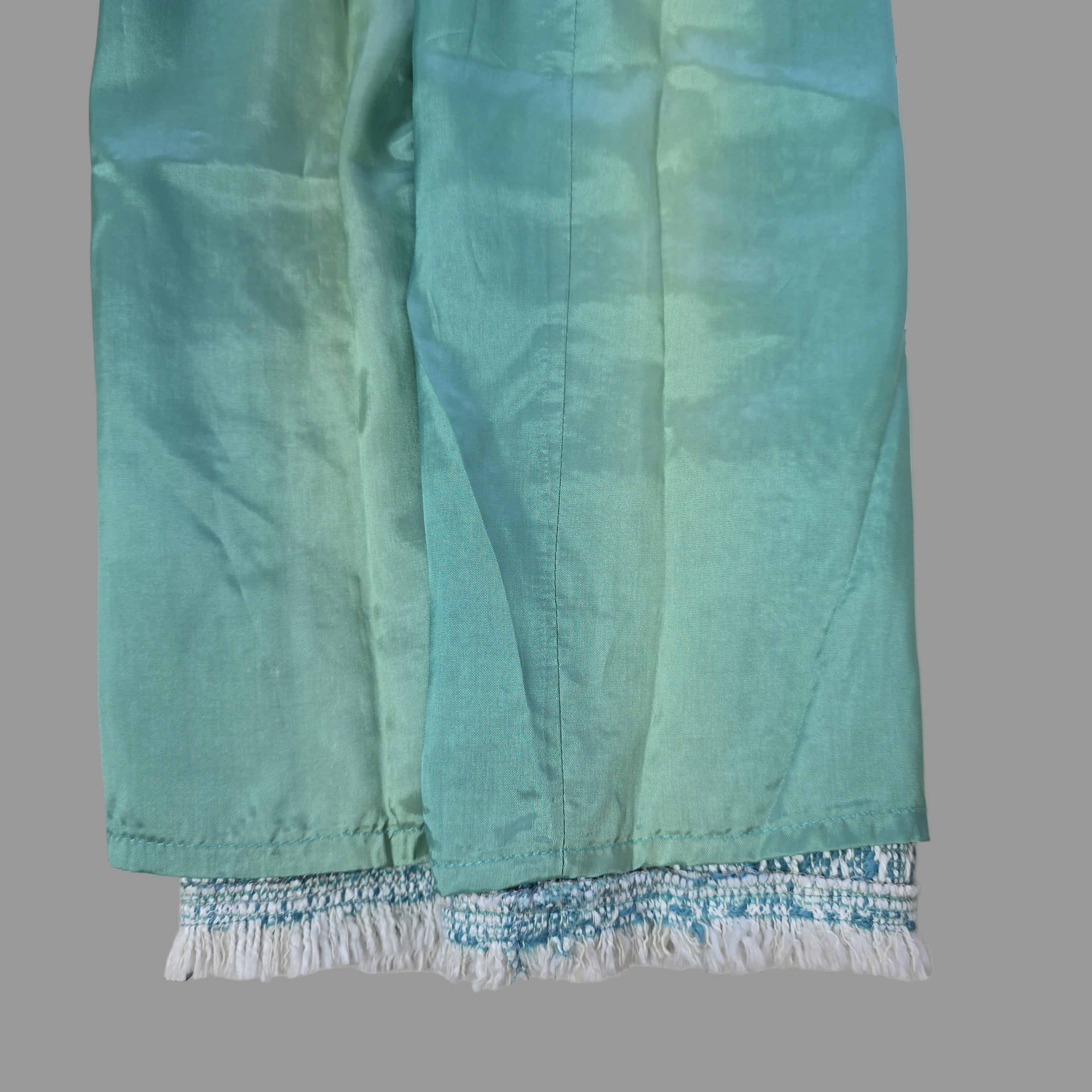 Teal fabric with white fringe on a tiled floor