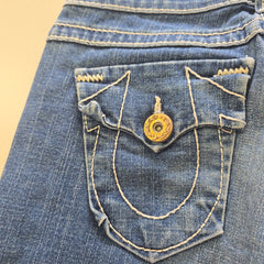Close-up of a blue denim pocket with a button on a beige background