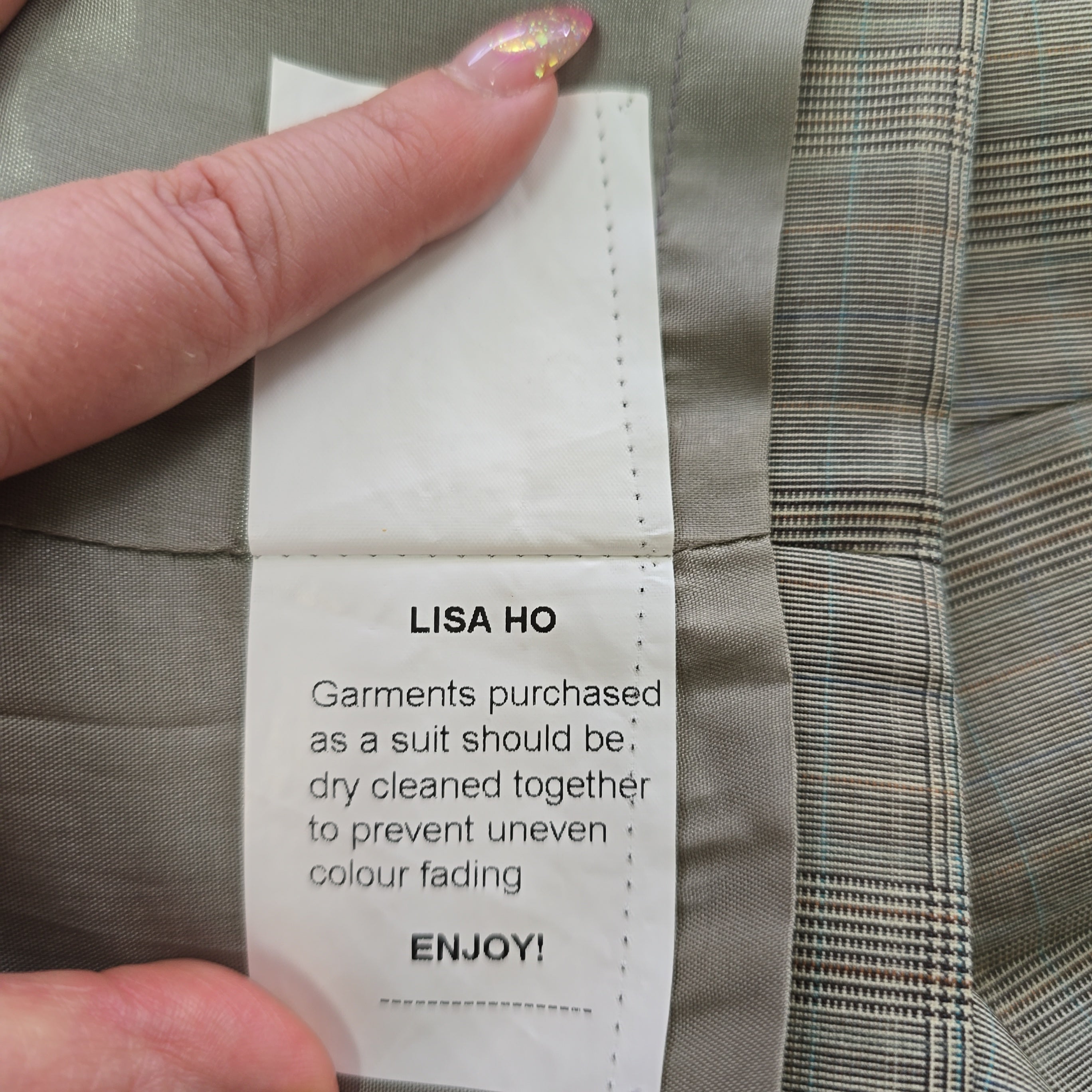 Close-up of a clothing label on a suit with a hand holding it.