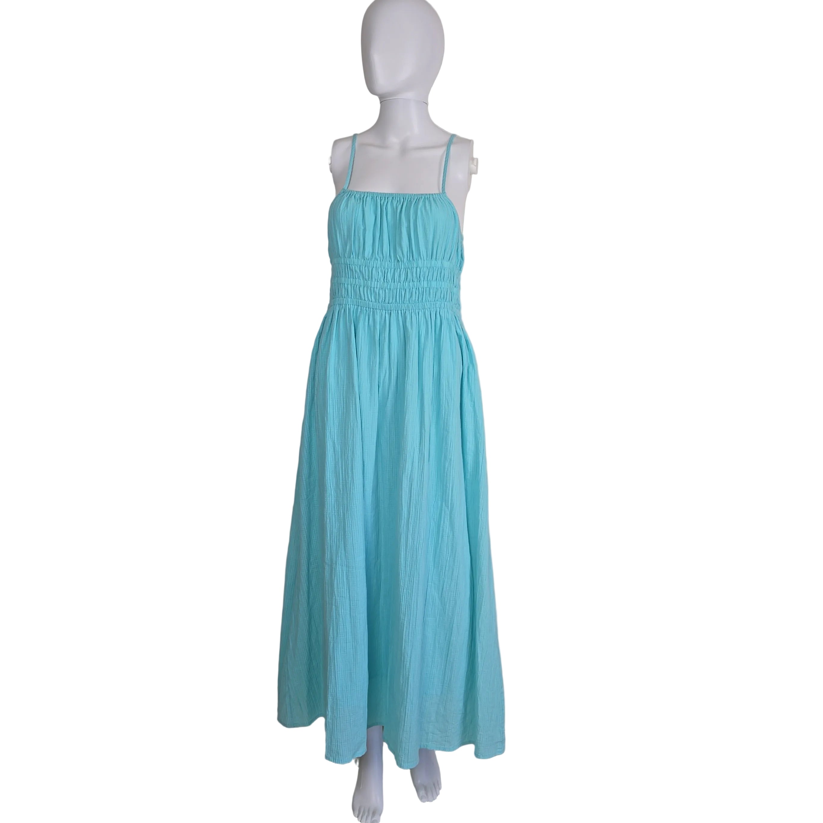 Turquoise dress on a mannequin against a white wall.