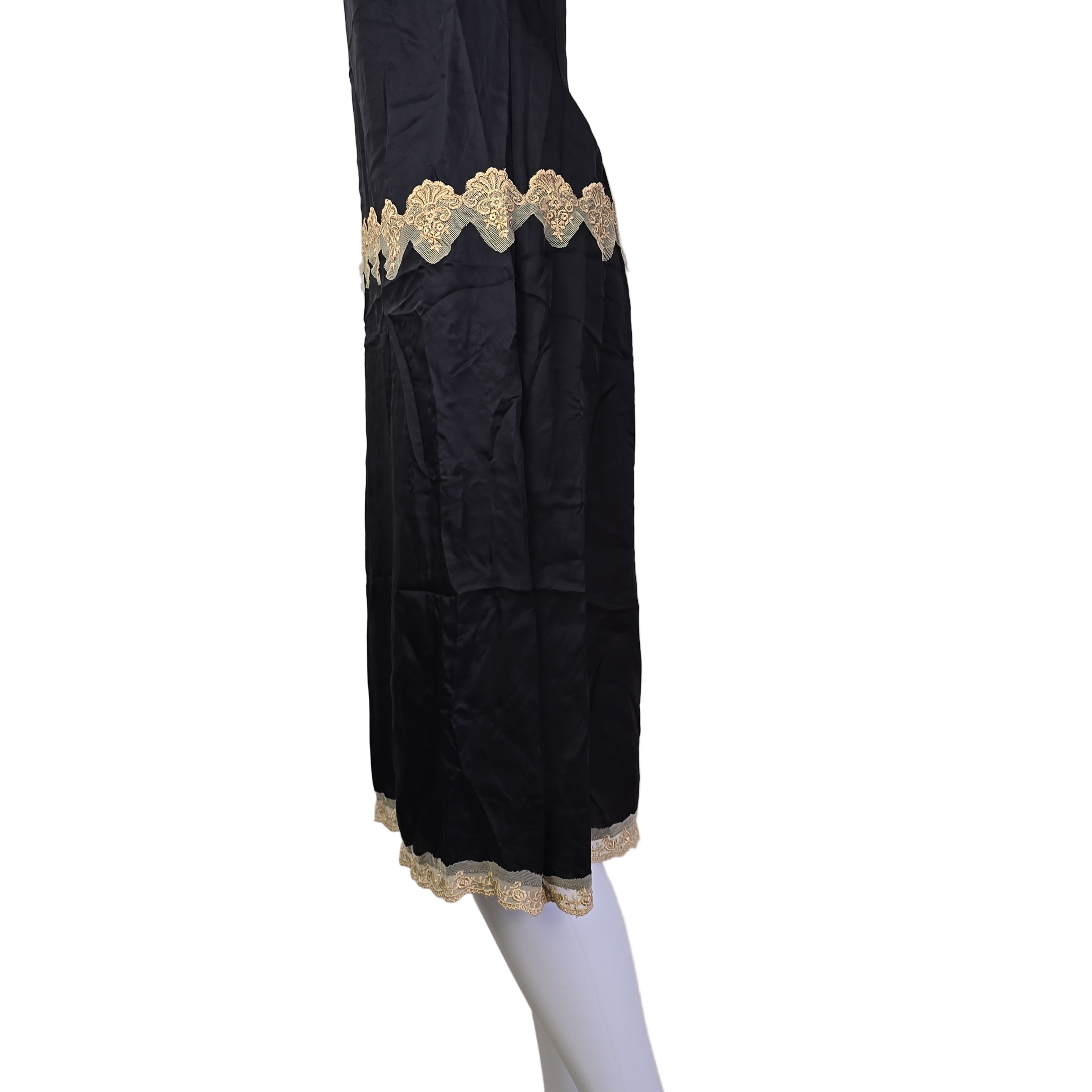 Black garment with gold lace trim on a white surface