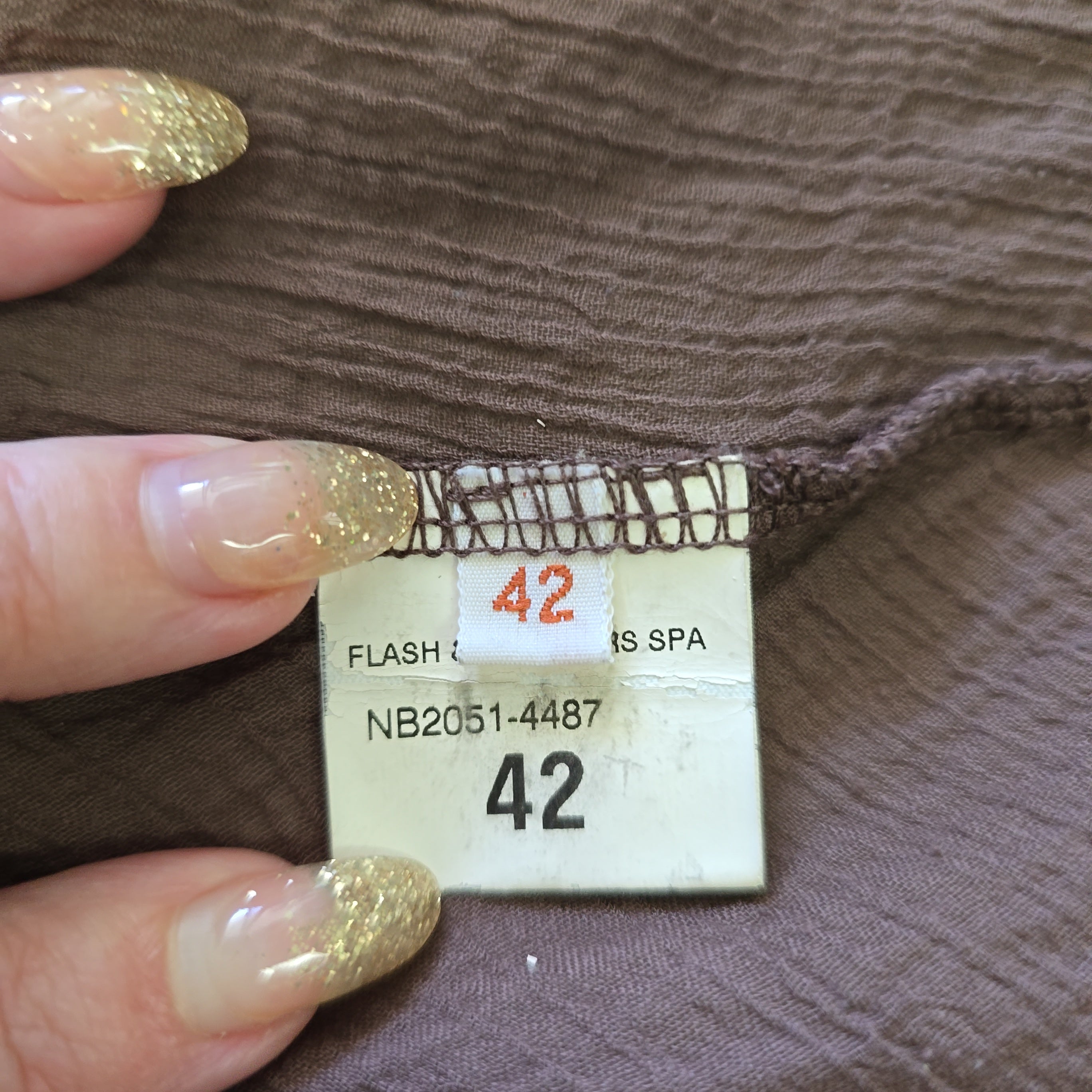Close-up of a clothing tag with size 42 on brown fabric.