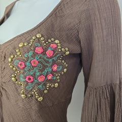 Brown fabric with floral embroidery and gold studs on a white background