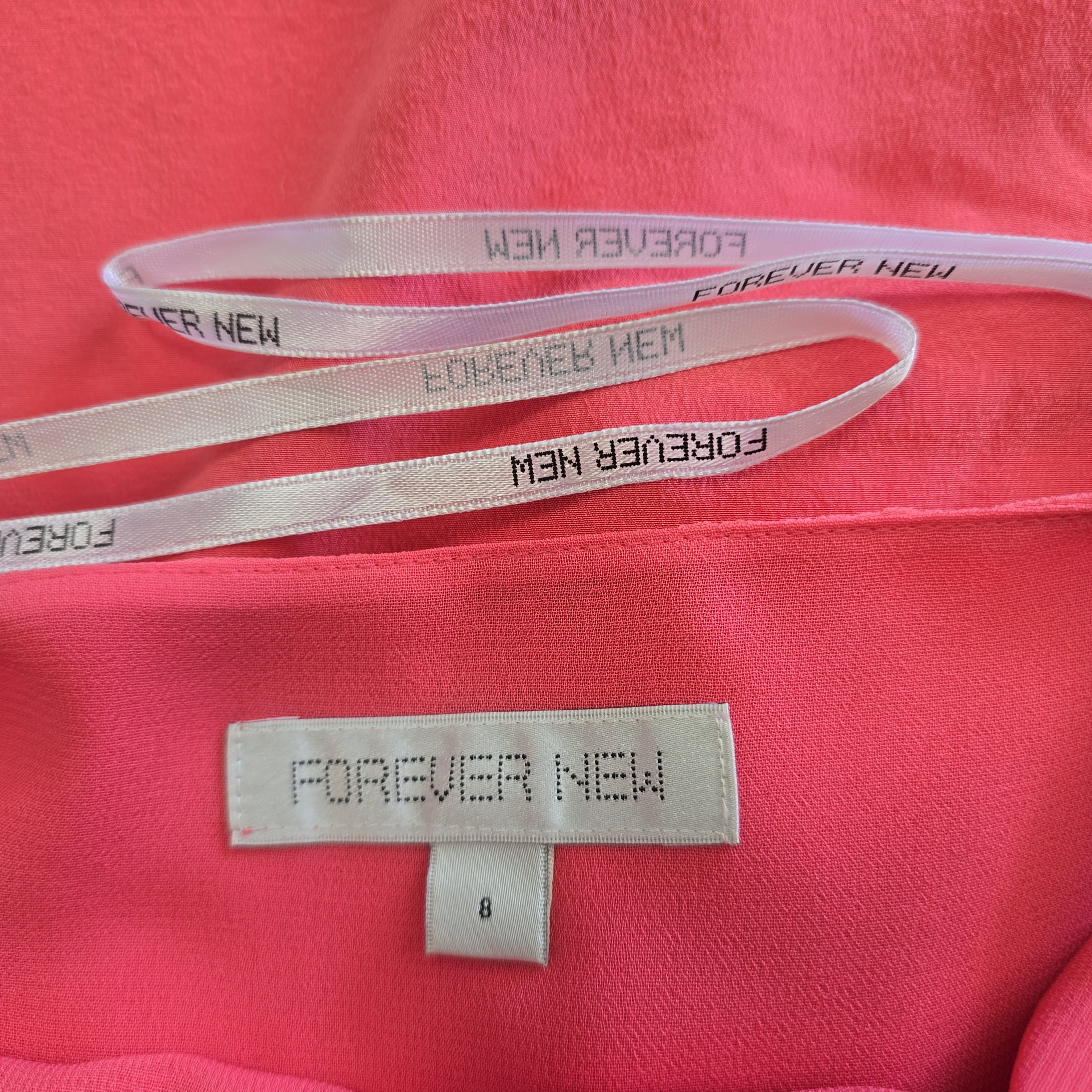 Close-up of a pink garment with 'Forever New' branding on a strap and label.
