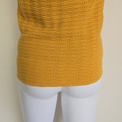 Mannequin wearing a mustard yellow knitted garment on a beige background