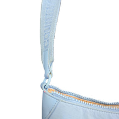 Close-up of a light blue bag with a zipper and strap on a light background