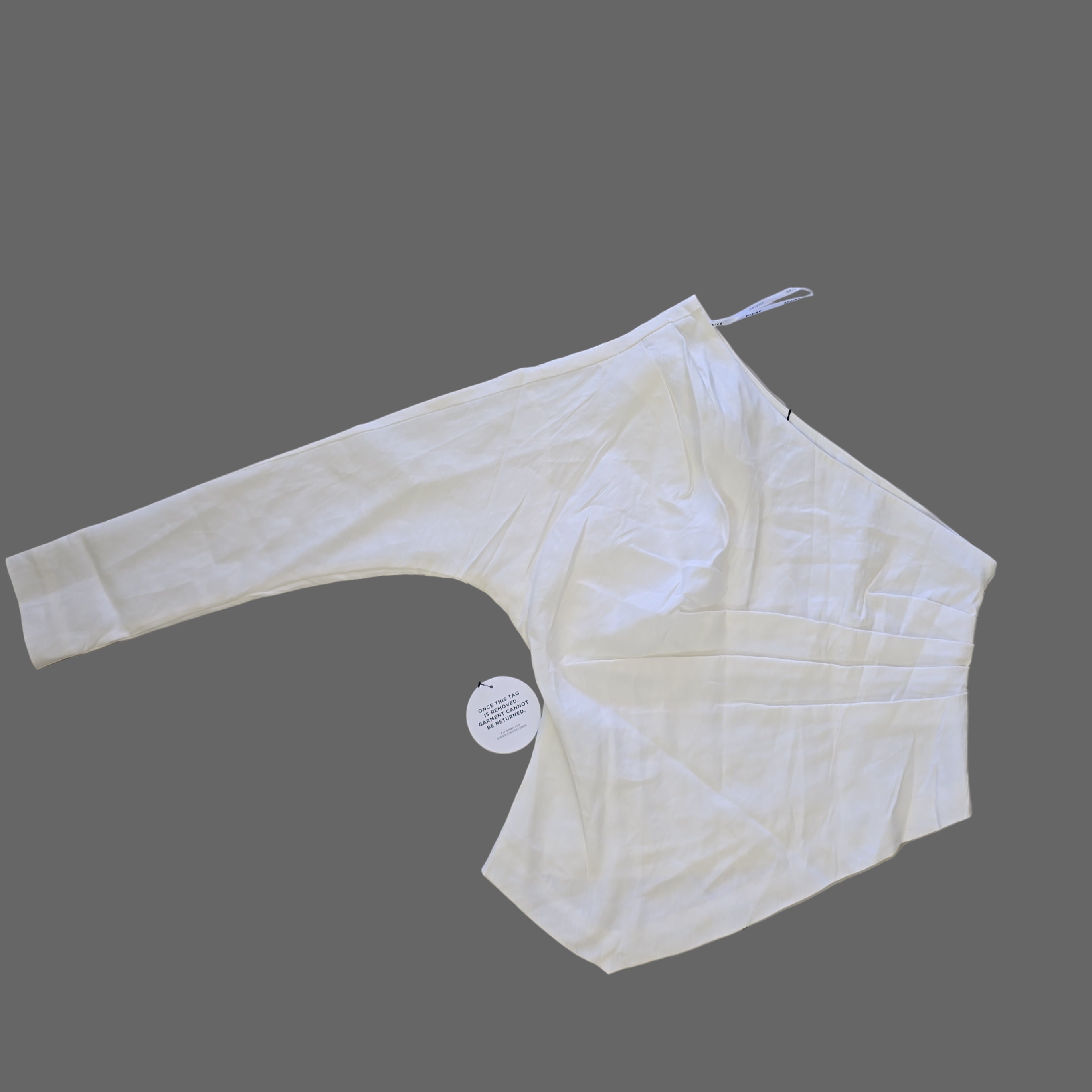 White top on a tiled floor with tags attached