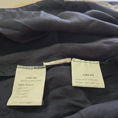 Close-up of a black jacket with 'LISA HO' labels on a neutral background