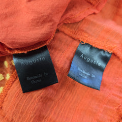 Close-up of orange fabric with 'Auguste' brand labels.