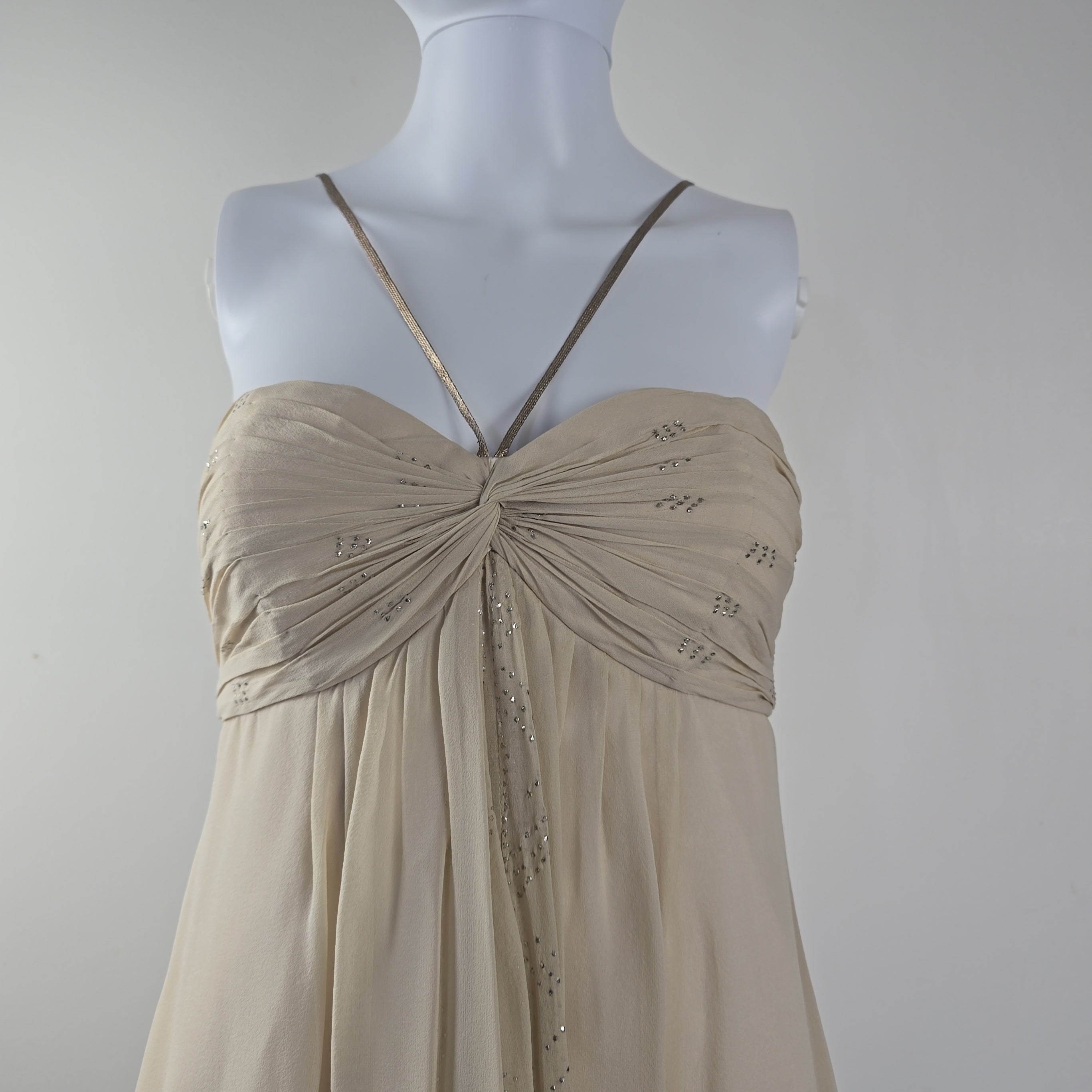 Beige evening gown on a mannequin against a plain background