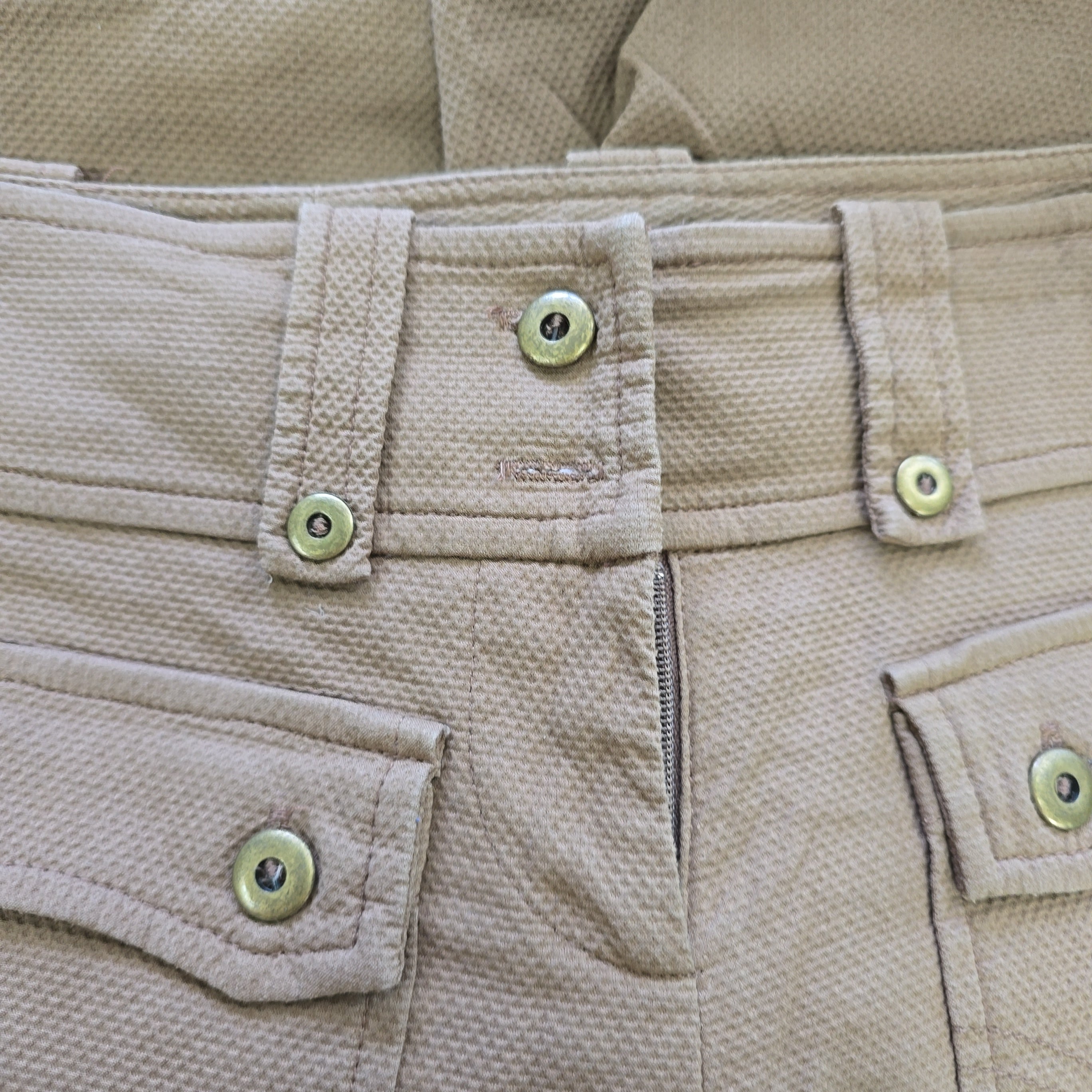 Close-up of beige fabric with buttons and zippers