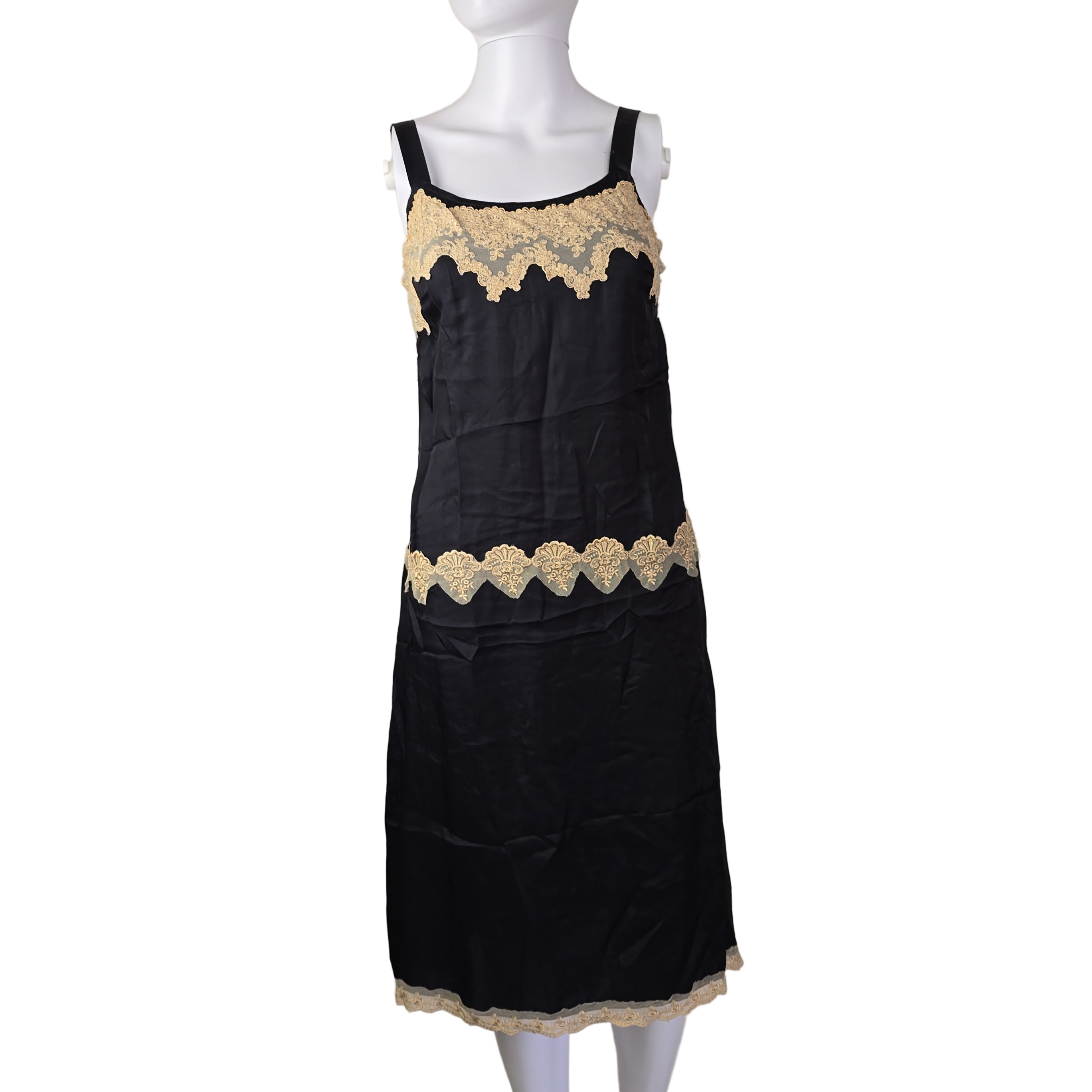 Black dress with gold lace trim on a mannequin against a beige background