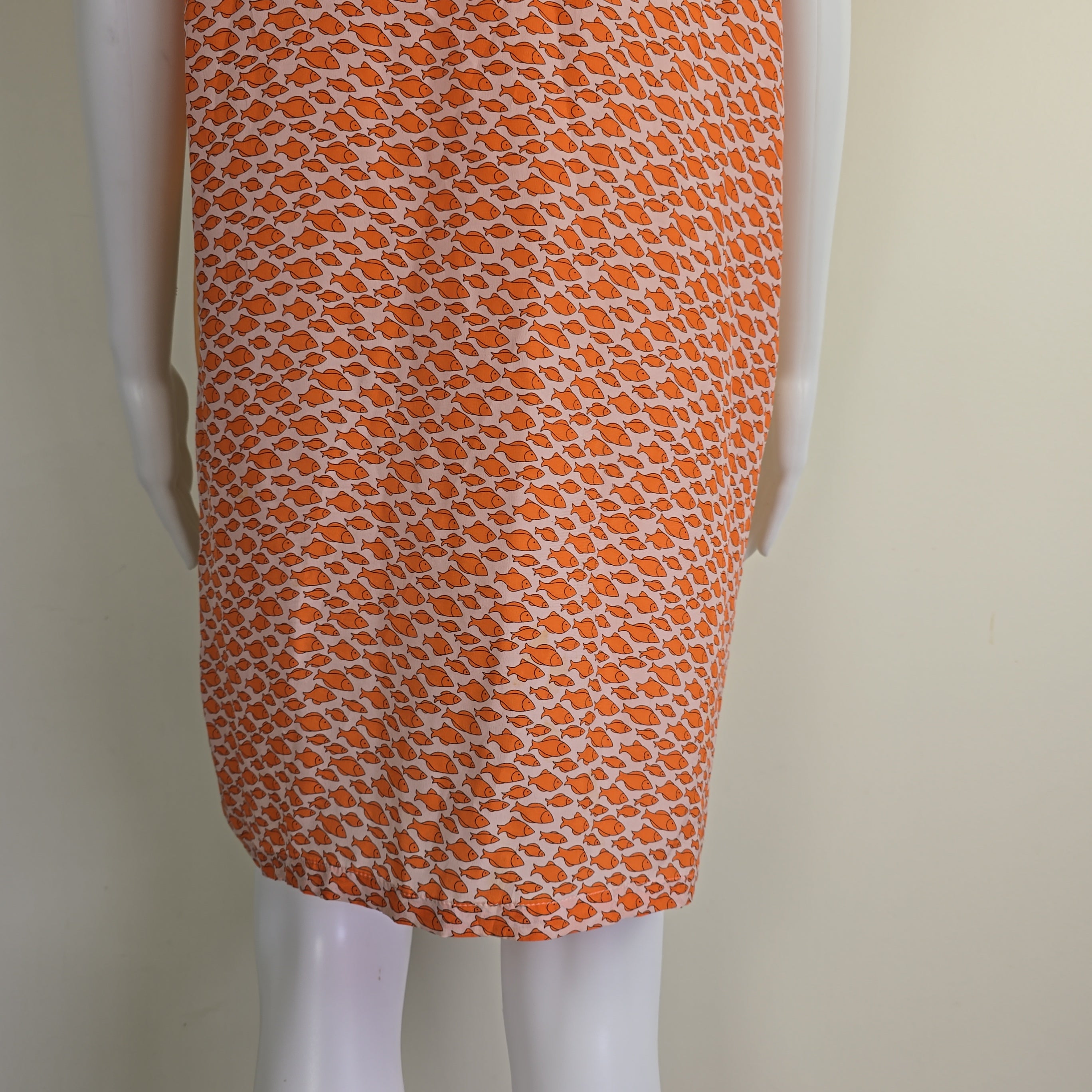 Orange patterned fabric on a mannequin arm against a beige background