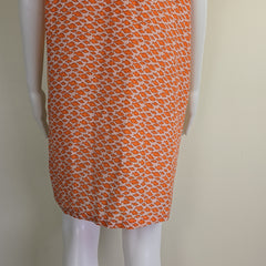 Orange patterned fabric on a mannequin arm against a beige background