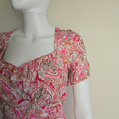 Mannequin wearing a pink and orange patterned garment against a beige background