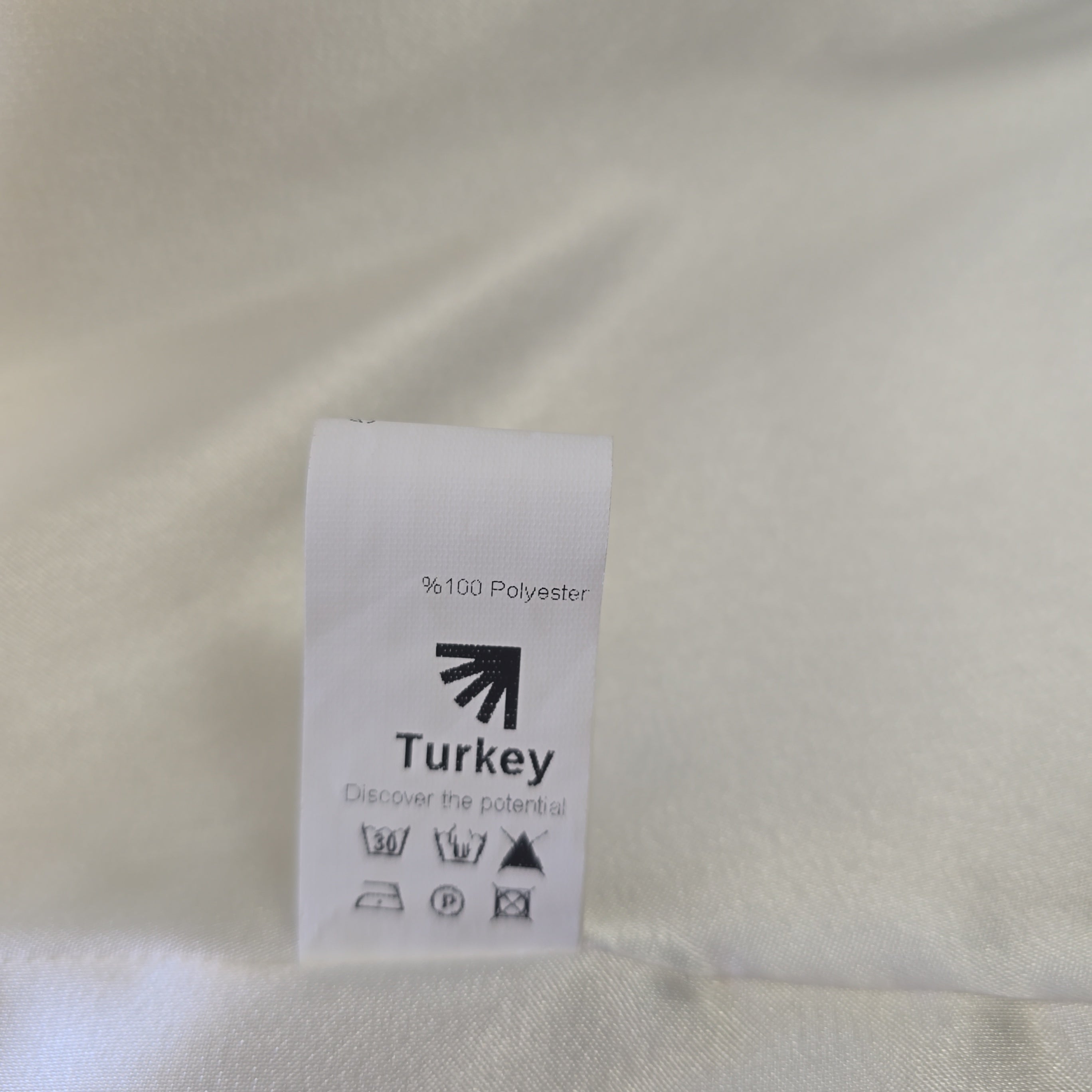 Fabric tag on a beige fabric background with 'Turkey' text.