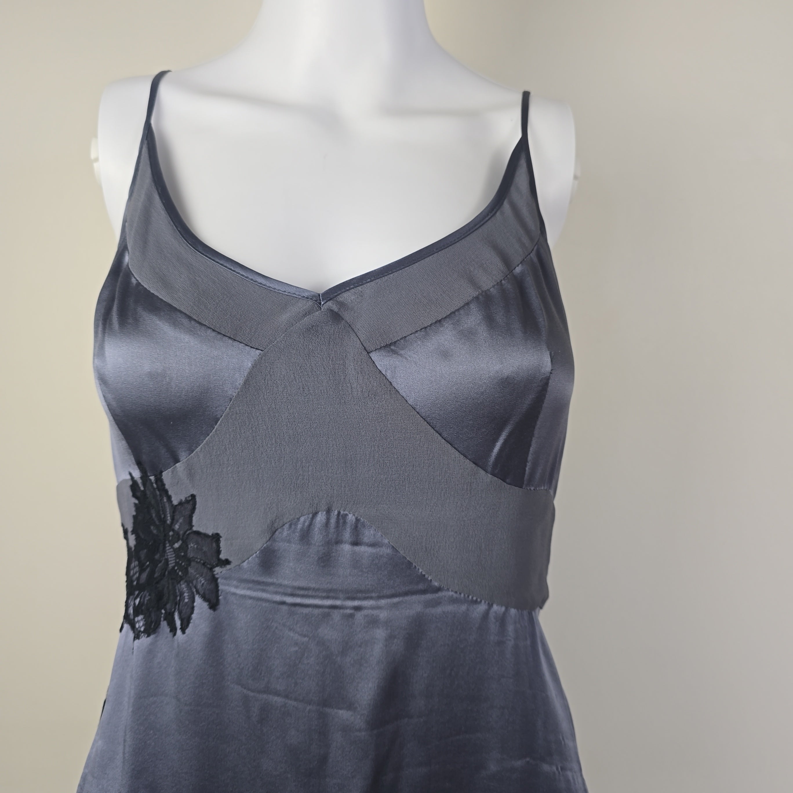 Gray satin dress with black lace on a mannequin against a beige background
