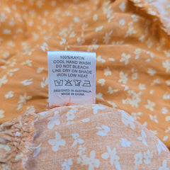 Close-up of a clothing label on an orange floral garment