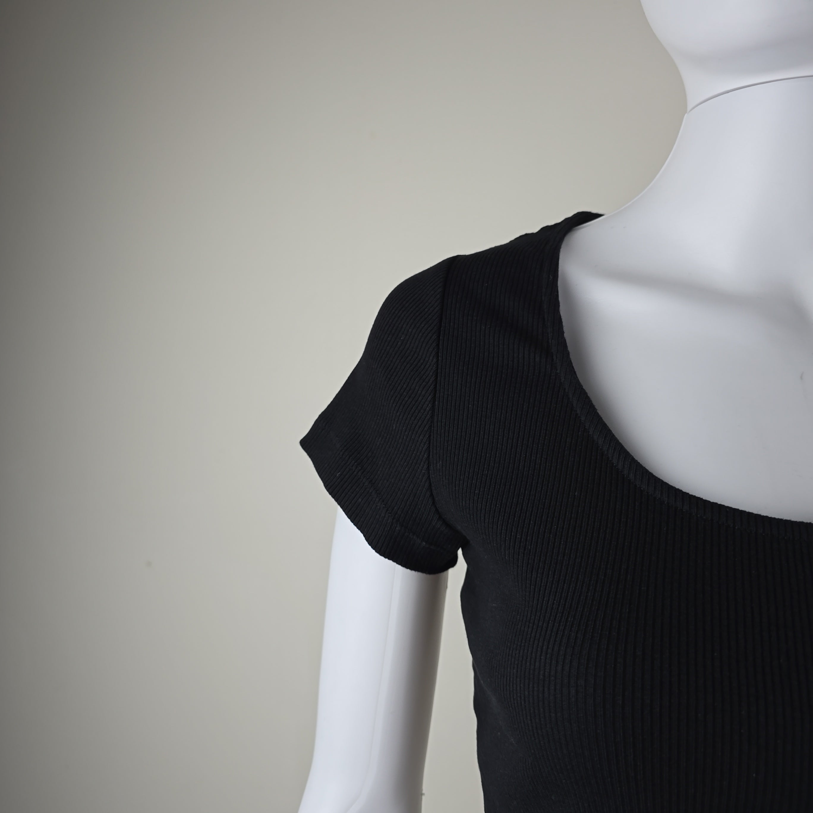 Black sleeveless top on a mannequin against a neutral background