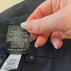 Close-up of a hand holding a clothing label with text and a brand logo.