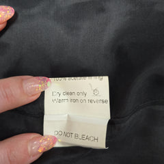 Clothing label on a black fabric with text indicating care instructions.