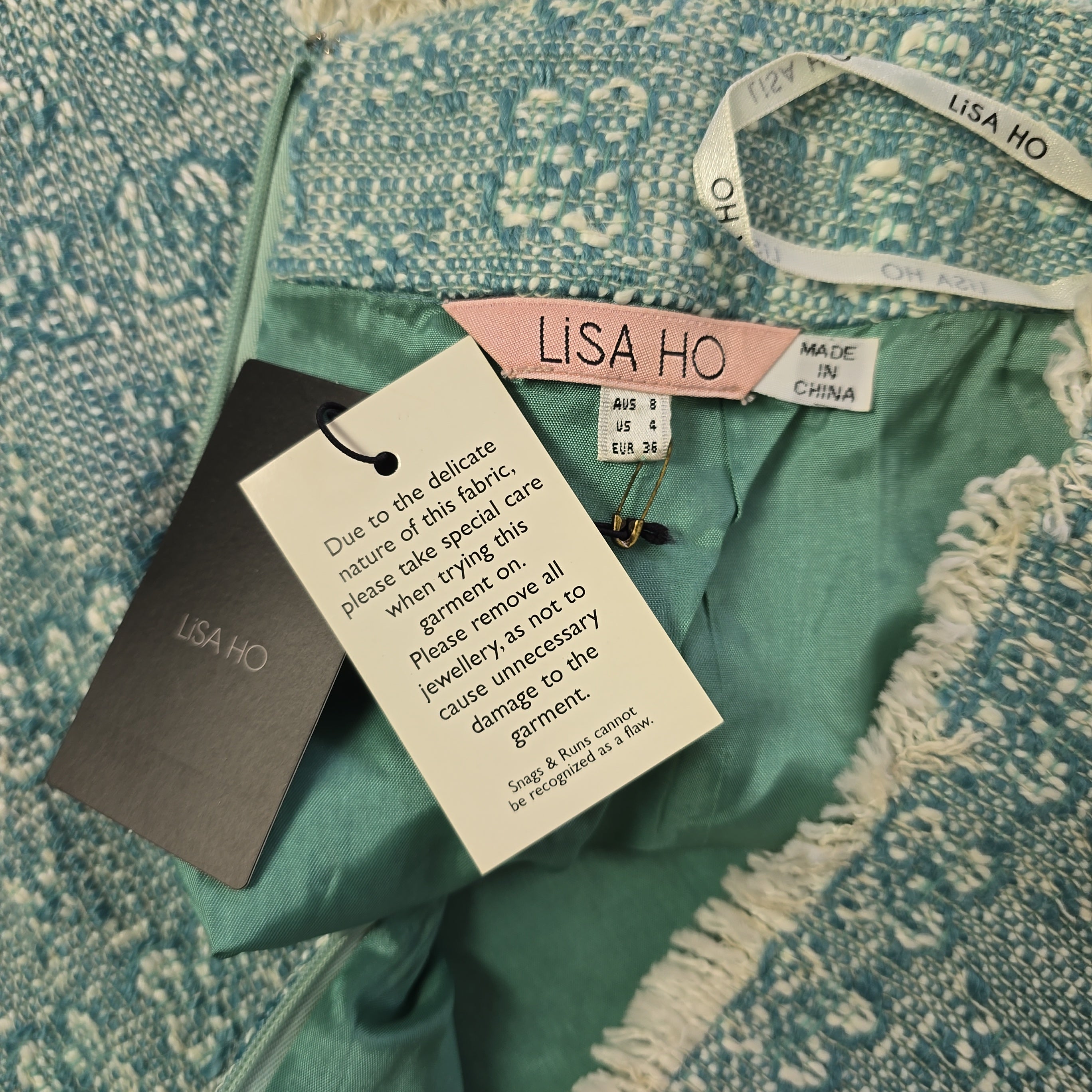 Green fabric with Lisa Ho tags and labels on a textured surface
