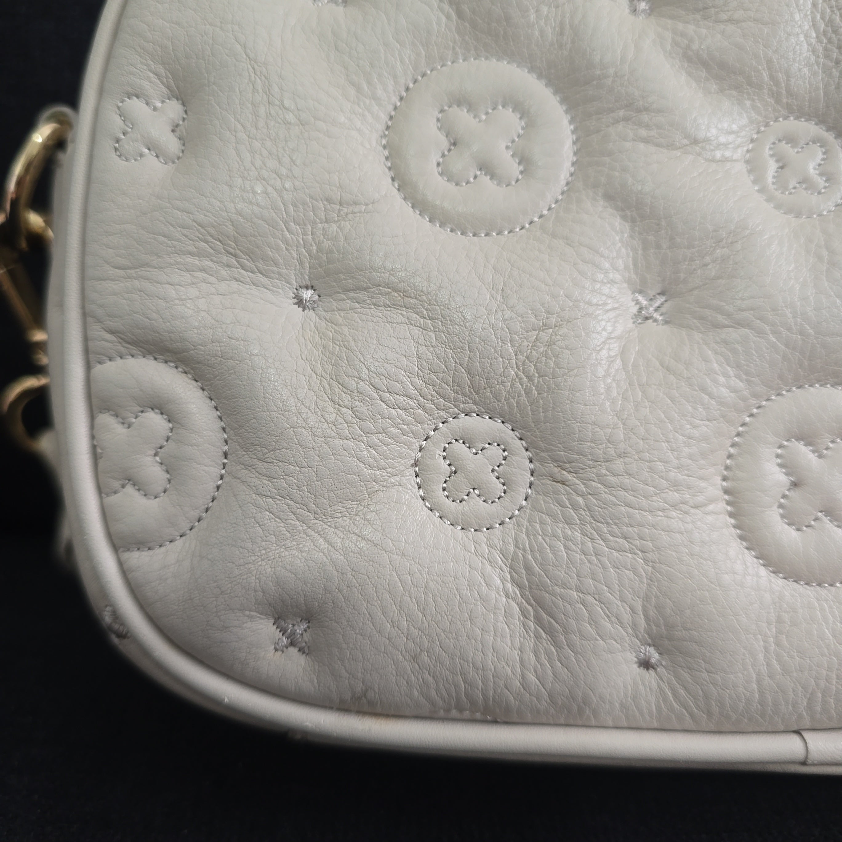 Close-up of a grey leather bag with circular patterns on a black background