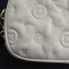 Close-up of a grey leather bag with circular patterns on a black background