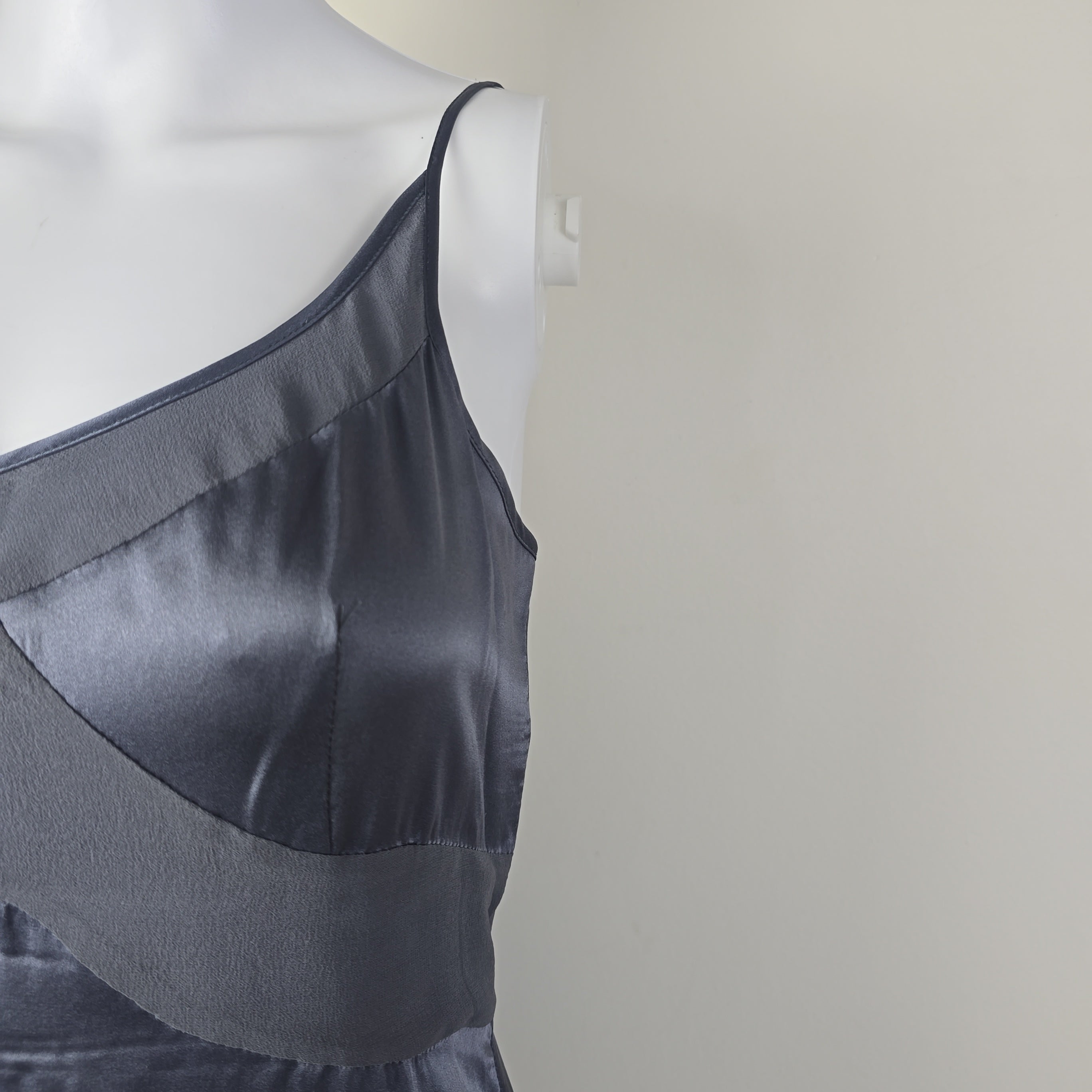 Dark grey satin garment on a mannequin against a plain background
