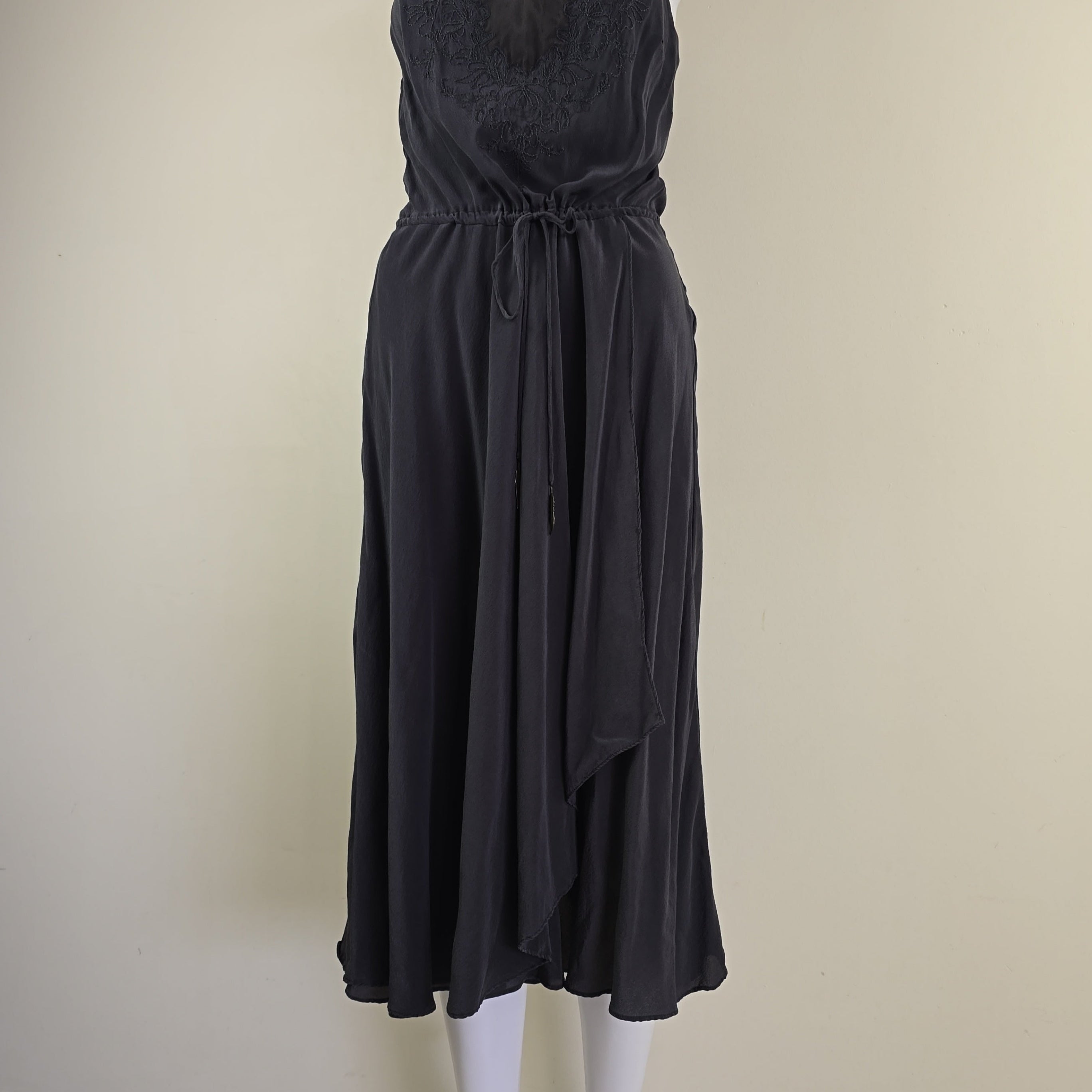 Grey pleated dress on a mannequin against a beige background